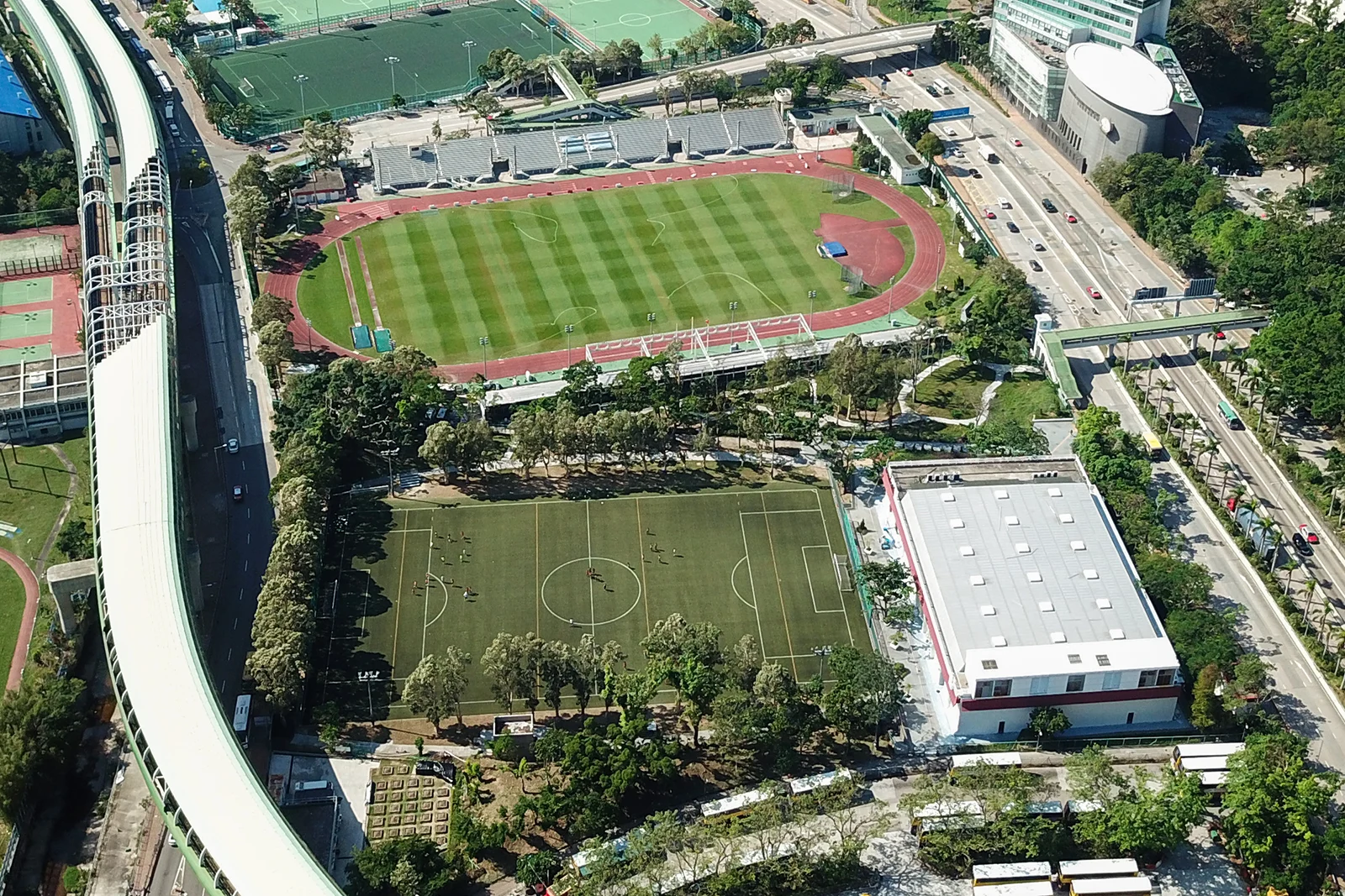 Aerial photograph of Aberdeen Sports Ground’s red track and green pitch, surrounded by roads, sports facilities and buildings in Hong Kong.