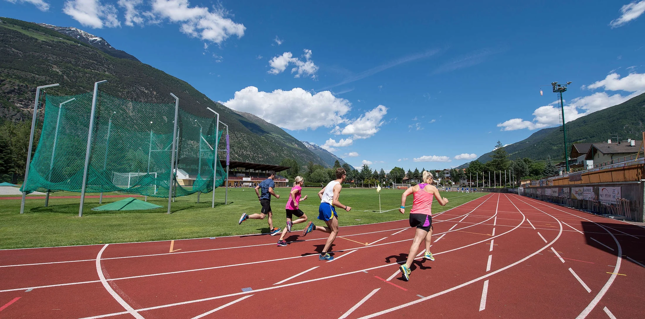 Runners on red lanes beneath the wooded and rocky slopes of the Vinschgau valley.
